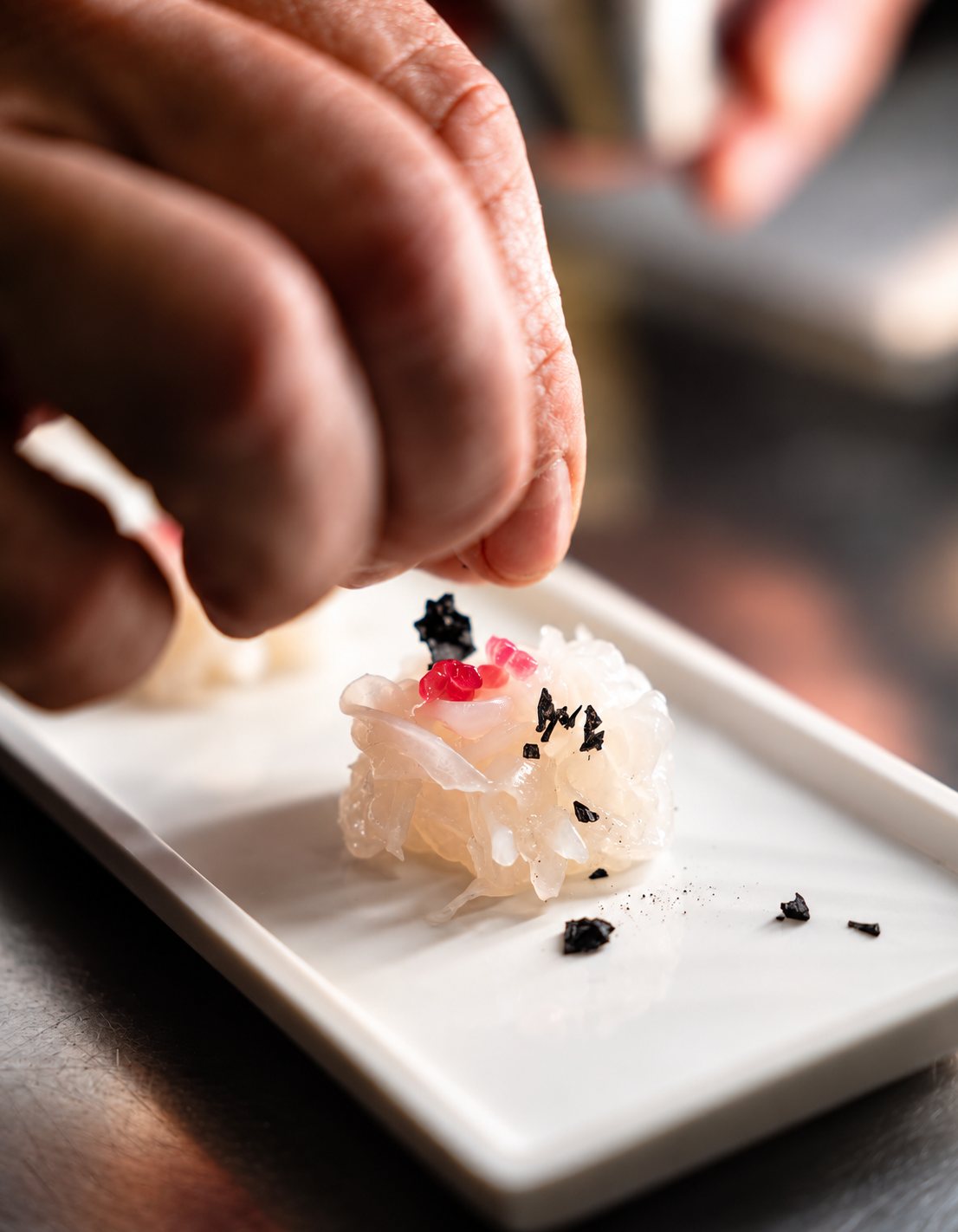 Crudo di mare guarnito a mano su piatto bianco